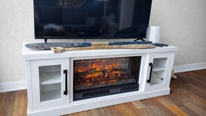 Una chimenea moderna con un televisor encima, un adorno en la repisa y un ambiente acogedor con suelo de madera.