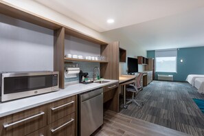 A modern hotel room with a kitchenette, a desk, a bed, and a large window. - Home2 Suites by Hilton Vero Beach I-95 (Vero Beach)