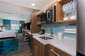 A modern hotel kitchen with stainless steel appliances, a sink, and a dish rack. - Home2 Suites by Hilton Vero Beach I-95 (Vero Beach)