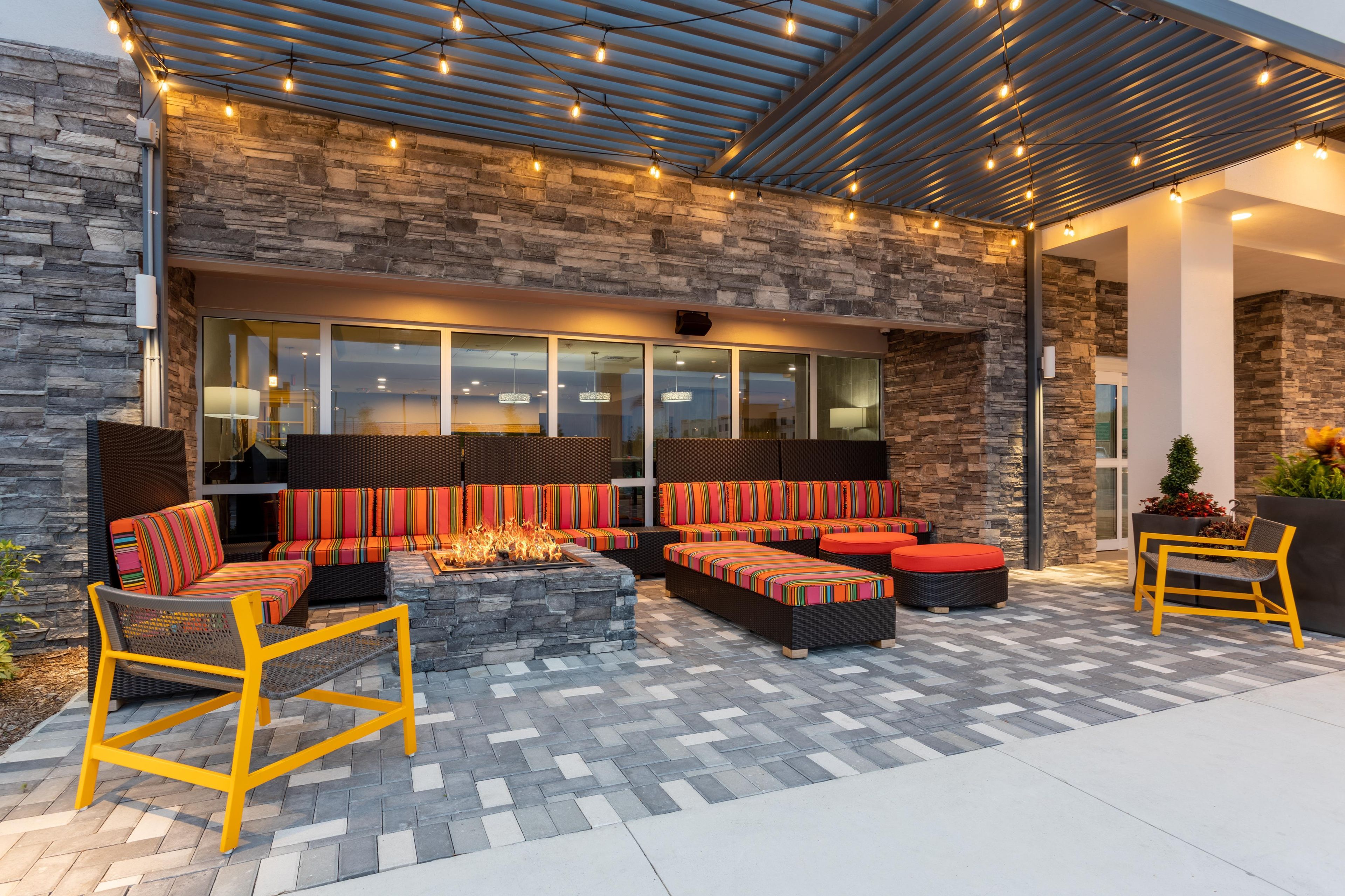 An outdoor seating area with stone walls, a fire feature, and modern furniture.