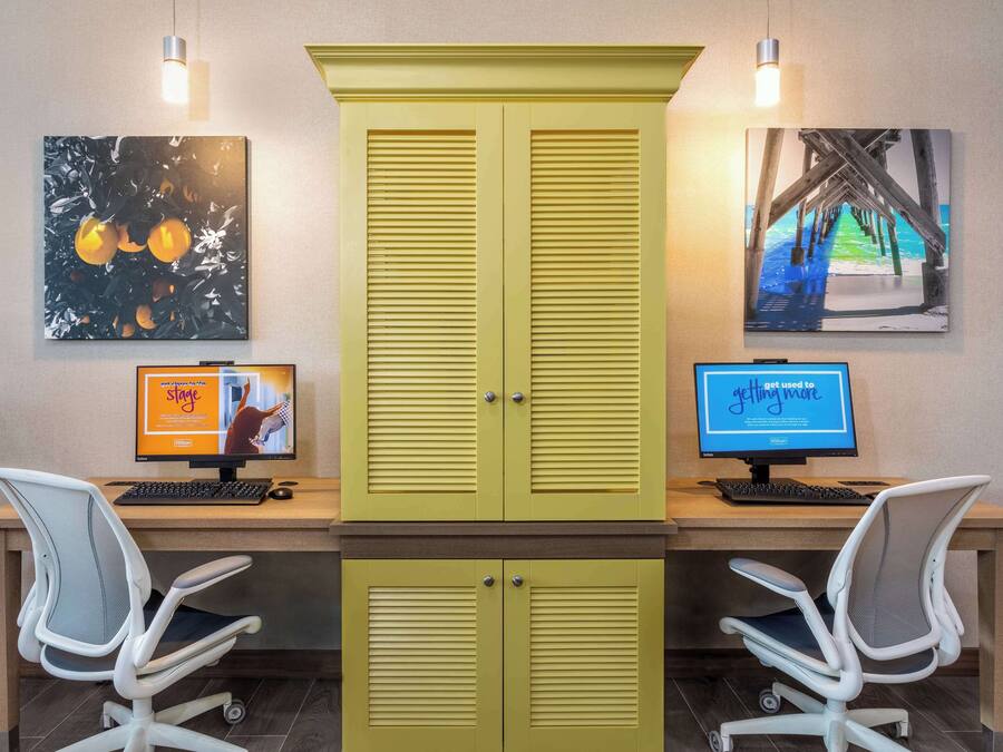 A workspace with two desks, each with a computer monitor, keyboard, and office chair.