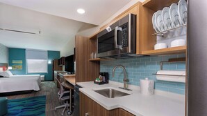 A modern hotel room with a kitchenette, a bed, and a bathroom. - Home2 Suites by Hilton Vero Beach I-95 (Vero Beach)