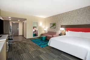 A hotel room with a bed, a desk, a chair, a sofa, and a small table.