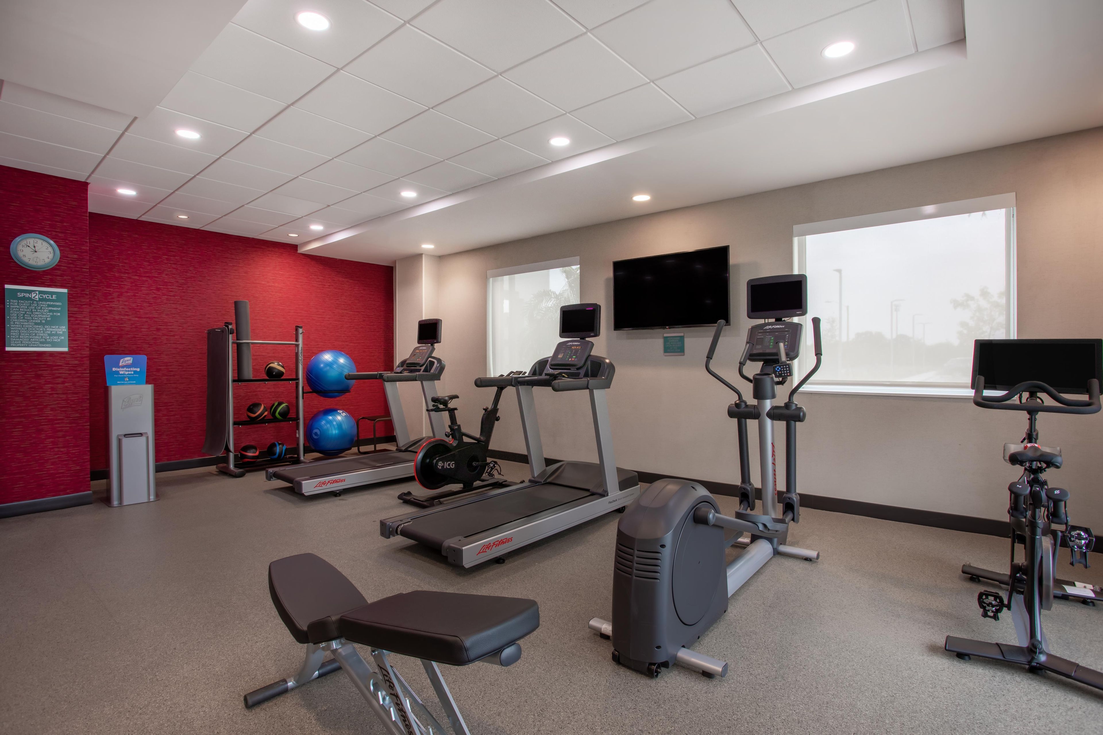 A gym with treadmills, stationary bikes, and exercise balls.