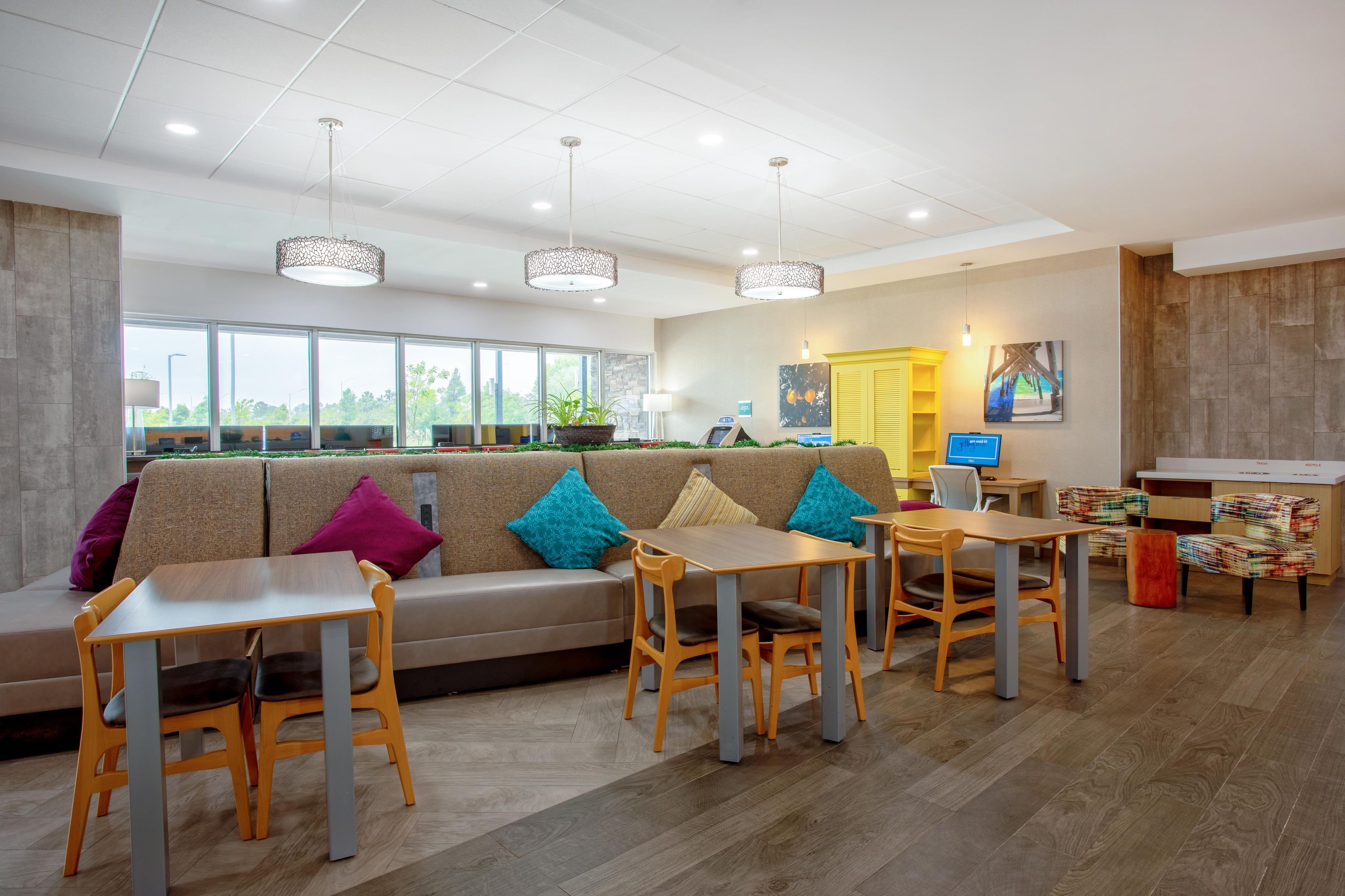 Un espace de détente intérieur moderne, comprenant un canapé, des tables, des chaises et un poste informatique.
