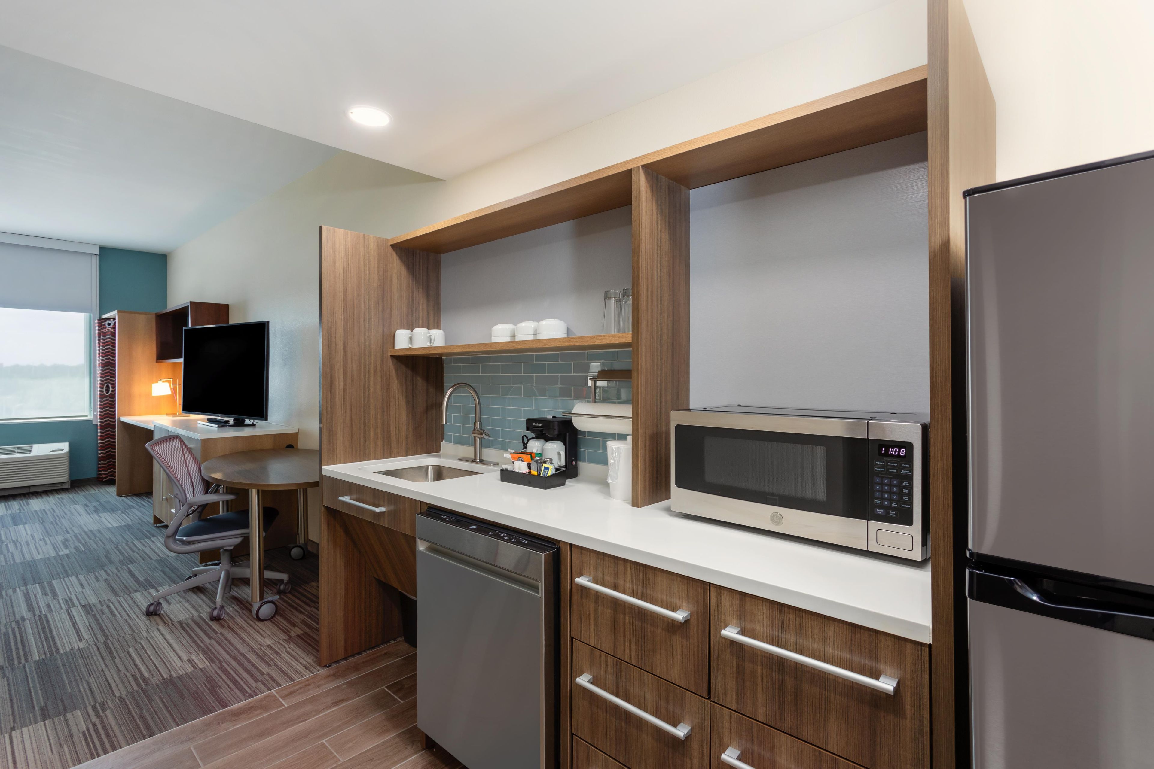 A compact hotel kitchen with a microwave, coffee maker, and a refrigerator.