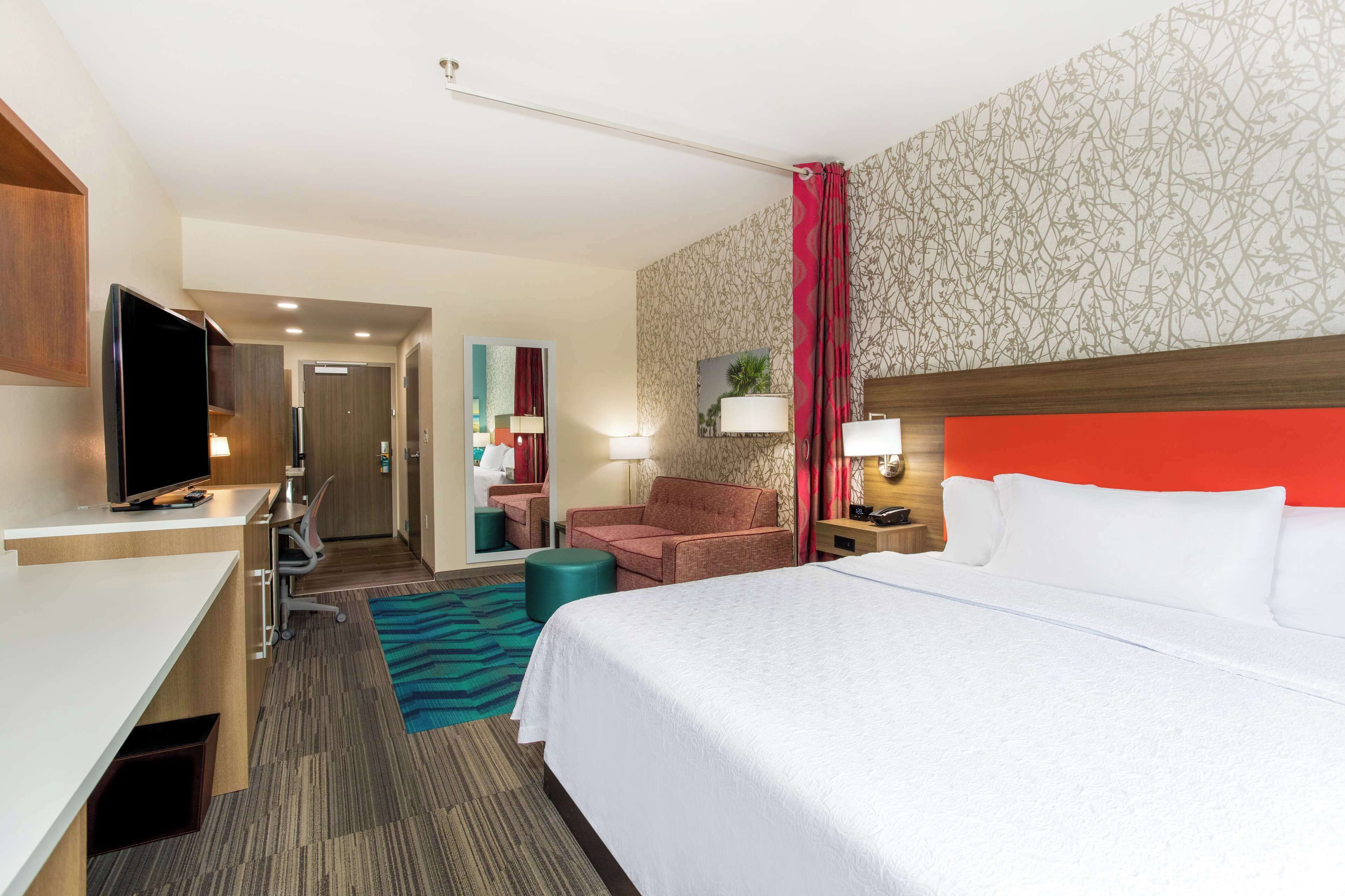 A hotel room with a bed, a desk, a television, a chair, and a bathroom.