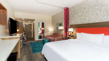 A hotel room with a bed, a desk, a television, a chair, and a bathroom.