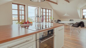 A modern kitchen with a wooden countertop, built-in oven, and large windows offering a view of the city. - Penthouse - 4BR - Downtown - Harbour (Tórshavn)