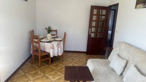 A living room with a sofa, a small table, and a dining table with chairs. - Appartement F2 Avec Jardin Cloture ET Fleurie (Medelo)