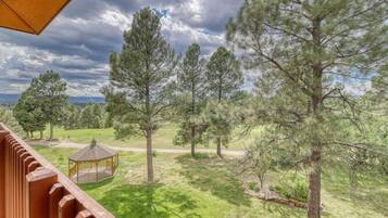 A view from a balcony overlooking a grassy area with trees and a gazebo.