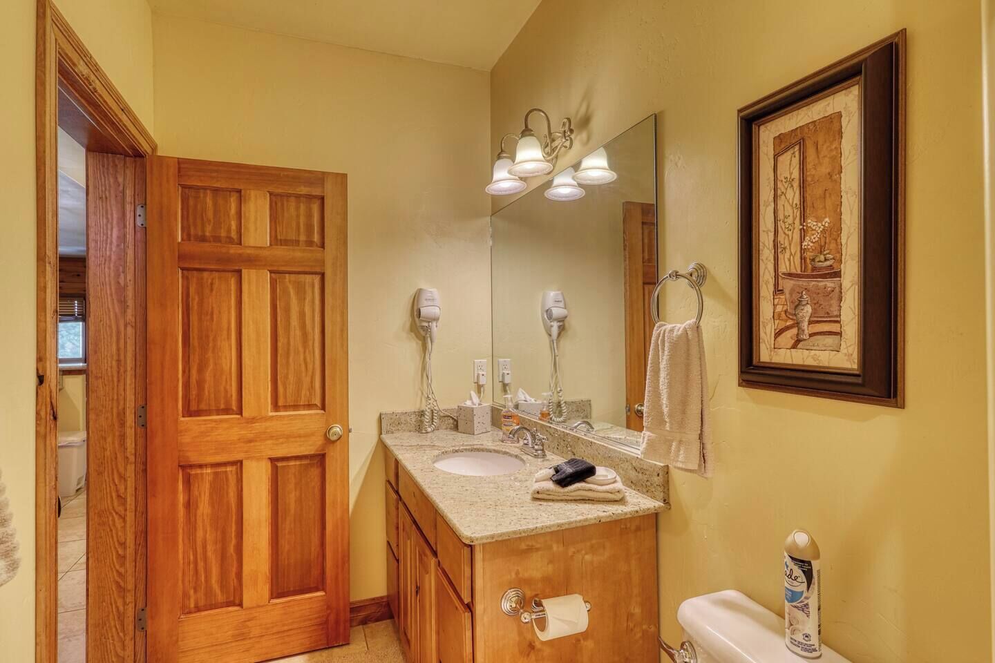 Ein Badezimmer mit Holztür, Waschbecken mit Spiegel, Handtuchhalter und Toilette.