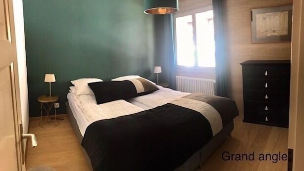 A bedroom with a bed, a nightstand, a lamp, a dresser, and a window.