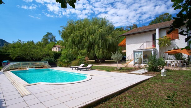 Une piscine avec des chaises longues, un patio couvert et une vue sur une montagne.