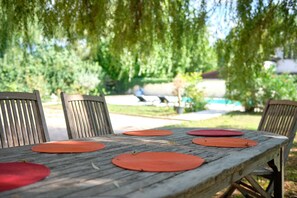 Ein Holztisch mit Platzsets und Stühlen im Freien.