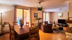 Un espace repas comprenant une table et des chaises en bois, un canapé, un téléviseur et une cheminée.
