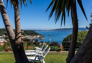 Vista costera con palmeras, un puerto deportivo y sillas de descanso.