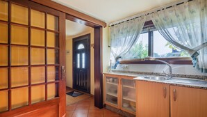 A kitchen with wooden cabinets, a sink, and a window with curtains. - "Casa Nueva de Bueu" with Mountain View, Wi-Fi, Garden & Terrace (Bueu)