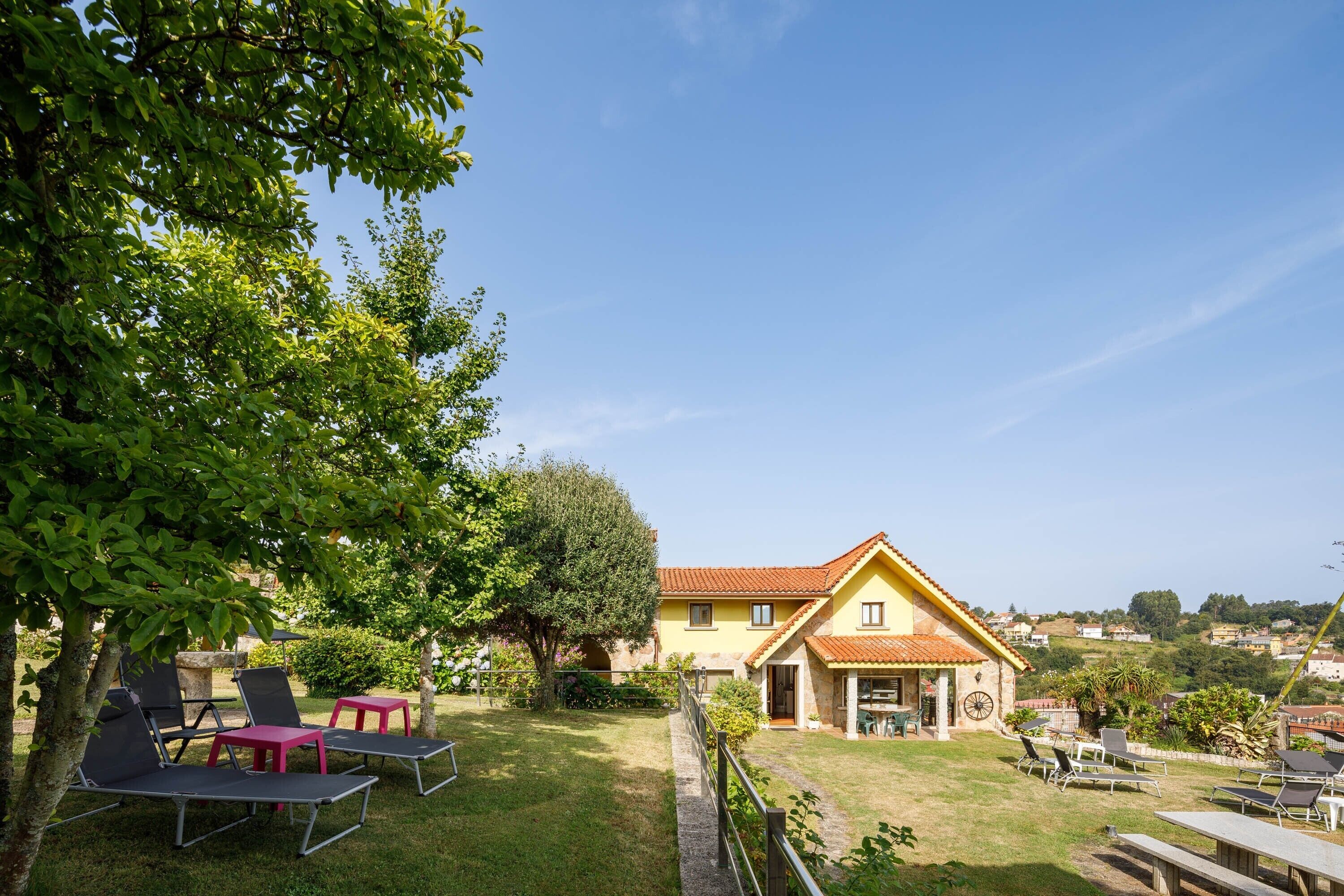 Une maison avec un jardin, un espace extérieur aménagé pour s’asseoir et une vue sur le paysage environnant.