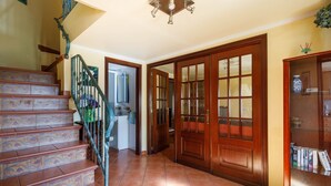 A staircase with ornate tiles, a wooden door with glass panels, and a ceiling light fixture. - "Casa Nueva de Bueu" with Mountain View, Wi-Fi, Garden & Terrace (Bueu)