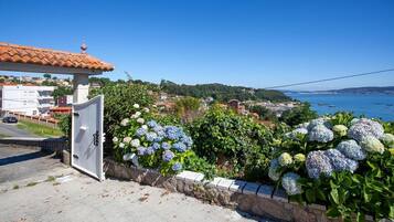 Une vue sur la côte, avec un mur de pierres, des arbustes d’hortensias et un bâtiment doté d’un toit en tuiles.