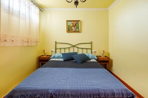 Un lit avec une couette bleue, deux oreillers, une tête de lit verte et une table de chevet avec une lampe.