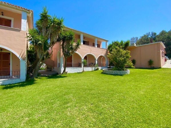A building with a courtyard, arched walkways, and palm trees.