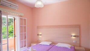 Ein Doppelzimmer mit zwei Betten, einem Balkonzugang und einem Deckenventilator.