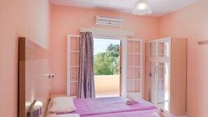 Een kamer met twee bedden, een balkon, een airconditioning en een spiegel.