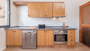 Eine kompakte Küche mit Holzschränken, einem Geschirrspüler, einem Backofen und einem Toaster.