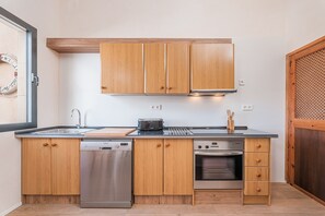 Une cuisine de taille réduite, dotée de meubles en bois, d’un lave-vaisselle, d’un four et d’un grille-pain.