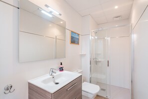 A modern bathroom with a white sink, mirror, and toilet.