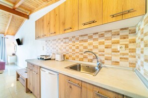 A kitchen with wooden cabinets, a tiled backsplash, a stainless steel sink, and a countertop with a toaster.
