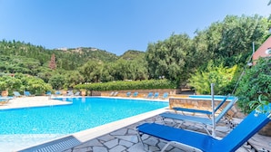 A swimming pool with lounge chairs, surrounded by greenery and hills. - Studio Apartment 'Arianna Superior Studio 19' with Shared Pool & Wi-Fi (Corfu)