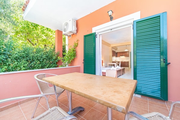 An outdoor patio with a table and chairs, a sliding door, and a view into the interior.