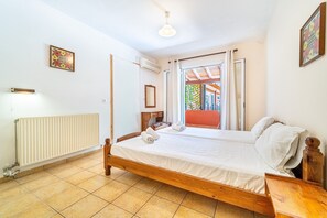 A bedroom with a wooden bed, a radiator, a window with curtains, and a ceiling light.