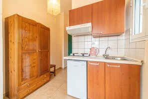 Cocina compacta con armarios de madera, lavavajillas integrado, cafetera y aire acondicionado de pared.
