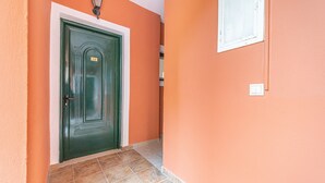 Ein Korridor mit einer grünen Tür, orangefarbenen Wänden und Fliesenboden.