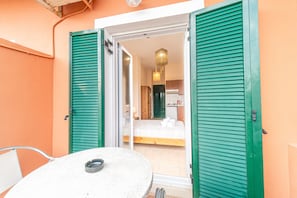 Una habitación con cama, una mesa y una silla, con vista al interior por una puerta.