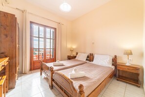 Ein Schlafzimmer mit zwei Holzbetten, einem Holzschrank, einem Fenster mit Vorhängen und einem Nachttisch mit Lampe.
