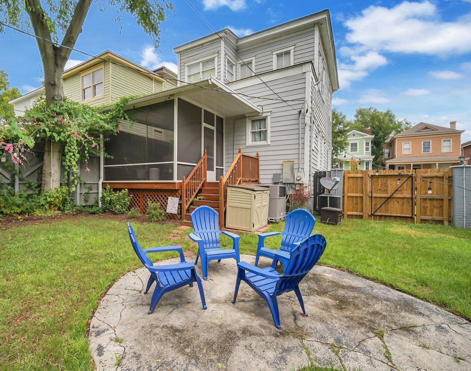 A house with a covered patio, a screened porch, and a backyard with a lawn and a wooden deck.