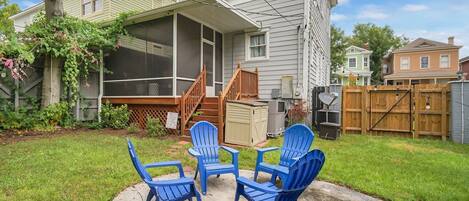 A house with a covered patio, a screened porch, and a backyard with a lawn and a wooden deck.