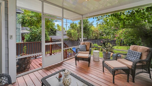 A covered patio with wicker furniture, a ceiling fan, and a view of a backyard.