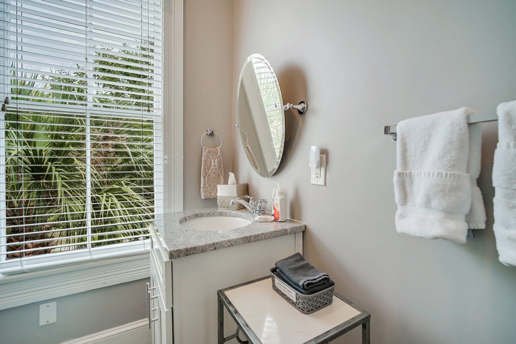 Ein Badezimmer mit Fenster, Waschbecken, Spiegel und Handtuchhalter.