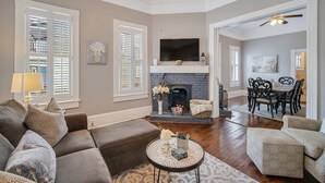 A living room with a fireplace, a sofa, a coffee table, and a dining area with chairs.