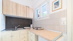 Een keuken met houten kastjes, een spoelbak, een waterkoker en een aanrecht met een koffiezetapparaat.