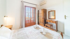 Een slaapkamer met een bed, een houten garderobe, een bureau, een spiegel en een raam met gordijnen.