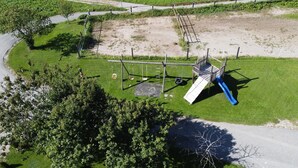 Luchtbeeld van een speeltuin met een glijbaan, schommel en klimrek.