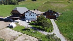 A rural property with a large white building, a smaller wooden structure, and a modern brown house.