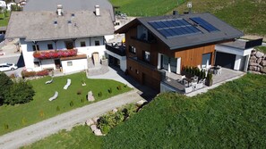 Un bâtiment à deux étages, doté d’un toit en pente, d’un balcon avec des sièges extérieurs et d’une allée pavée.